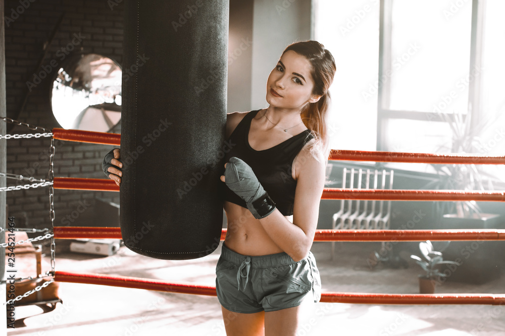 Young woman doing boxing training at the gym, she is wearing boxing gloves and hitting the punching bag