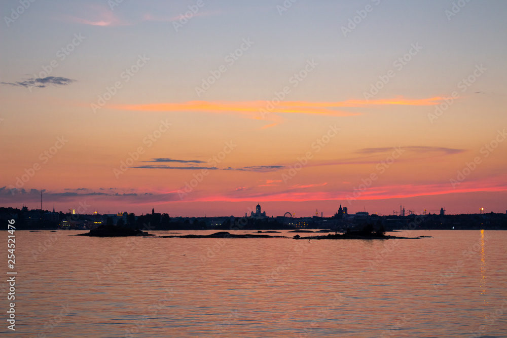 View of the silhouettes of the city of Helsinki from the Gulf of Finland at dusk on a bright summer night in the capital of Finland. Background with place for text.