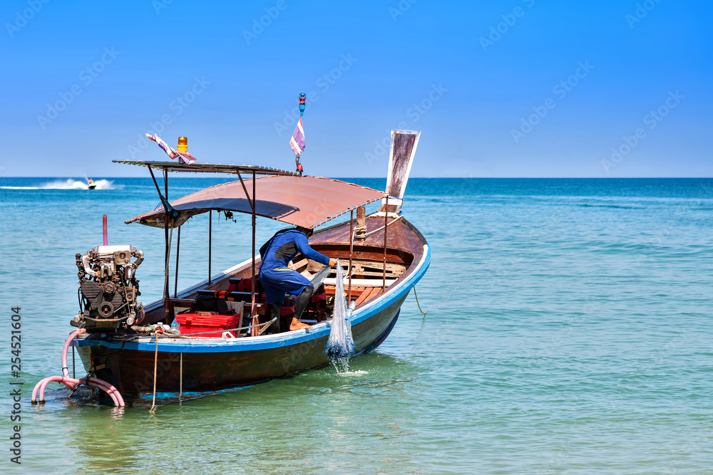 Fisherman on a motor wooden boat pull fishing nets. Sunny day, blue sky and sea. Fisherman on a motor wooden boat pull fishing nets. Sunny day, blue sky and sea.