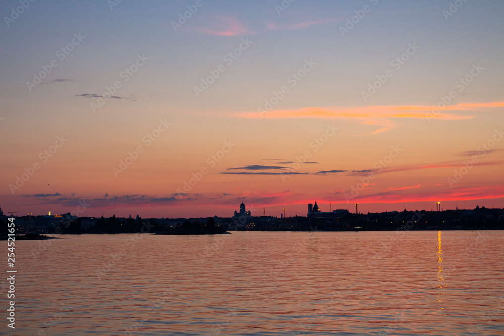 View of the silhouettes of the city of Helsinki from the Gulf of Finland at dusk on a bright summer night in the capital of Finland. Background with place for text.