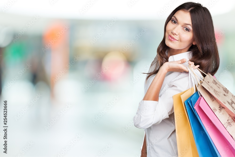 Young woman with shopping bags on blurred shopping mall background Young woman with shopping bags on blurred shopping mall background