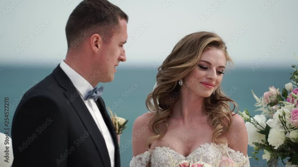 The bride and groom at the wedding ceremony. A young couple in love stands at the arch. Wedding by the sea. The bride and groom at the wedding ceremony. A young couple in love stands at the arch. Wedding by the sea.