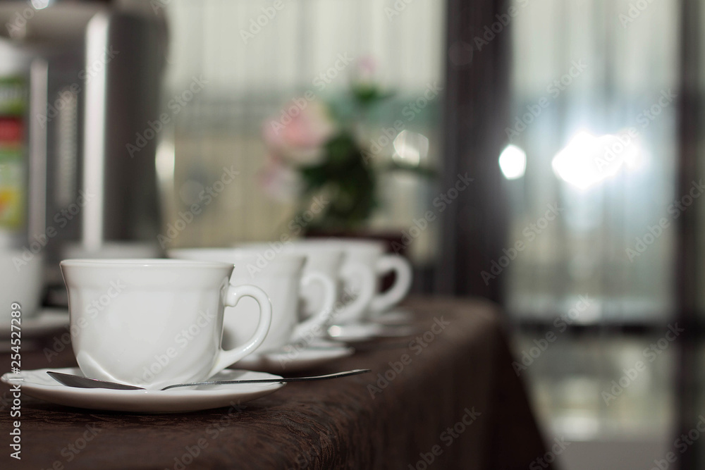 white cups of tea are in a row on the table with a brown tablecloth