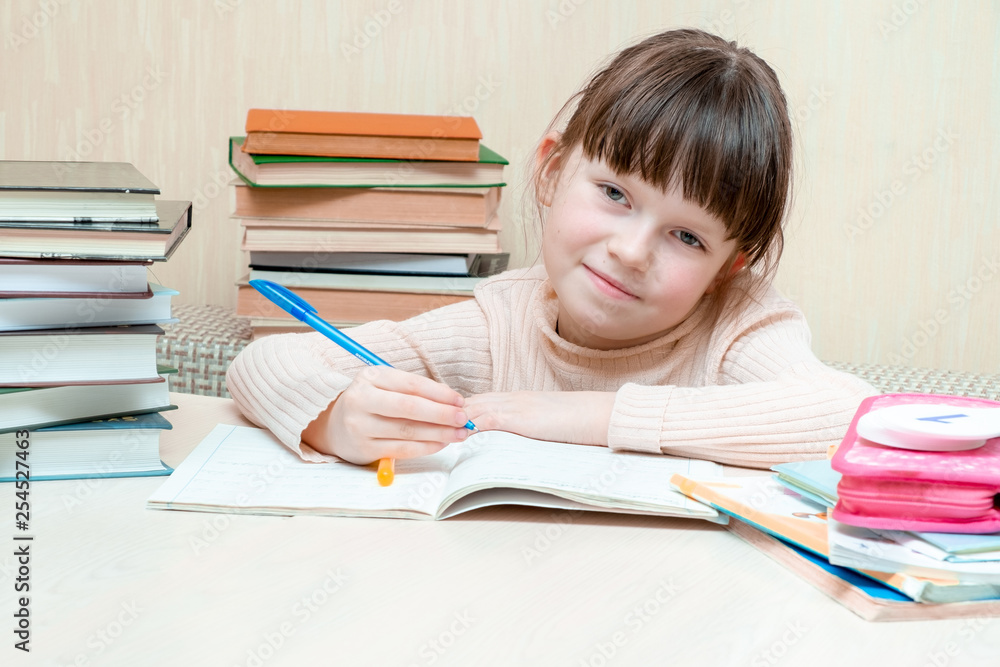 A tired child is sitting behind a notebook with a sad smile. In the right hand the child holds a fountain pen. A tired child is sitting behind a notebook with a sad smile. In the right hand the child holds a fountain pen.