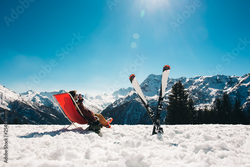 guy chilling out on the slope after skiing in Aprica ski resort with his skies next to him