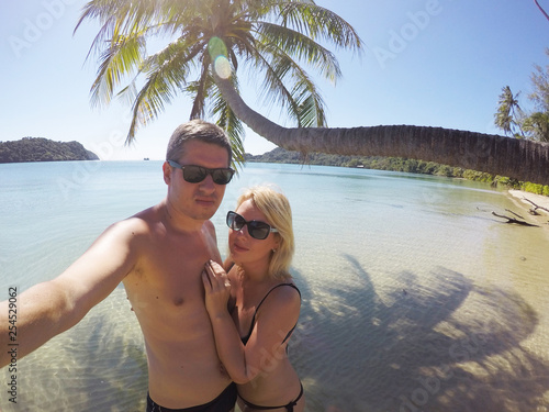 Fotografija Young couple sunbathing in a sea near palm at wild beach at summer vacation