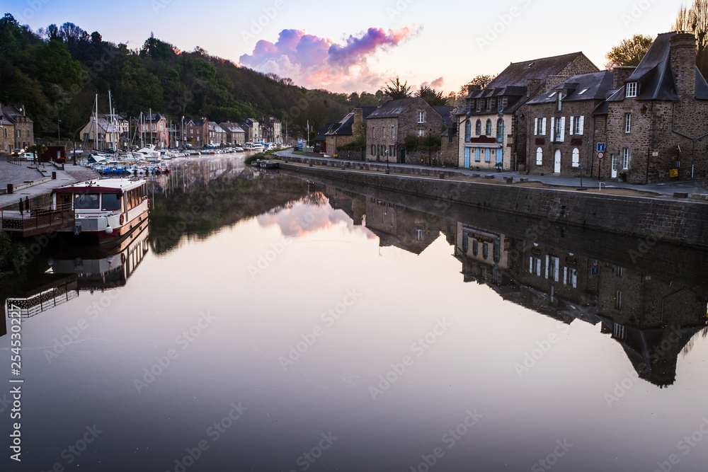 Fototapeta premium The small and quaint river port of Dinan on the very still River Rance, Côtes-d'Armor, France at sunrise