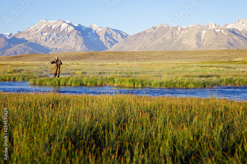 One man fly fishing on the Owens River at sunrise with the Sierra Nevada Mountains in the distance