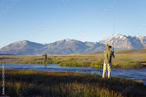 Two men fly fishing on the Owens river at sunrise with the Sierra Nevada Mountains in distance