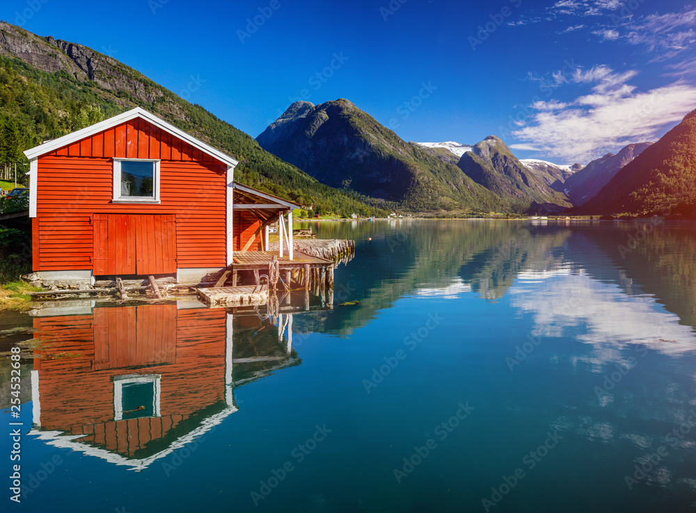 Beautiful fishing house on fjord. Beautiful nature with blue sky, reflection in water and fishing house. Norway