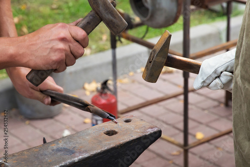 Work with hammers on the anvil in the street forge workshop.