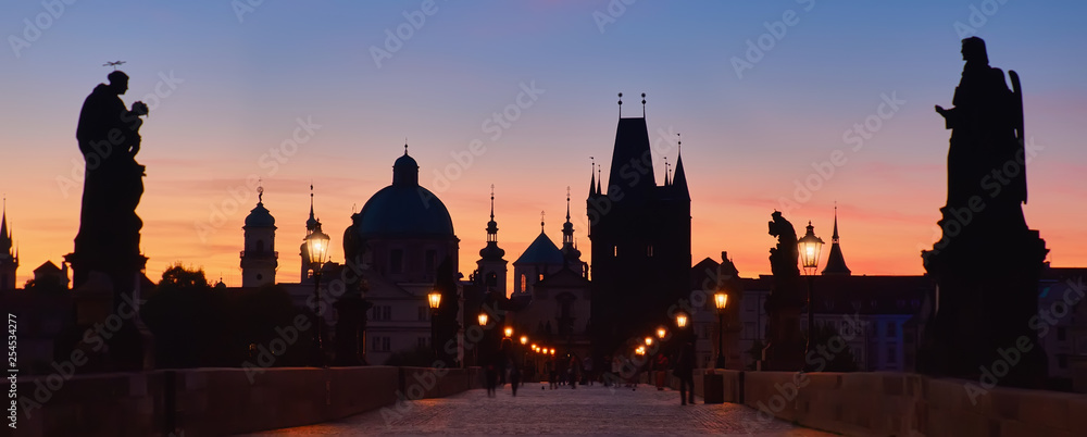 Fototapeta premium Prague at night, panoramic image. Charles Bridge early in the morning with unrecognizable tourists and photographers