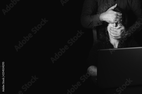 Woman typing on a computer with a hand covering her eyes and mouth photo