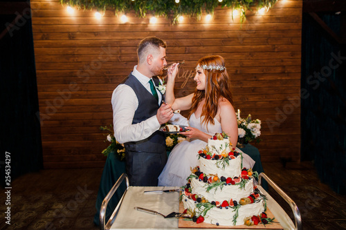 young beautiful wedding couple cuts the wedding cake and have fun