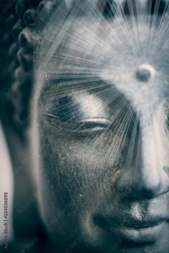 Soft spiritual sun rays on a buddha face close up shot. Buddhist religion concept idea