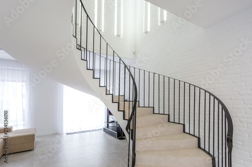 spiral staircase in bright interior with white brick wall in elite expensive apartment