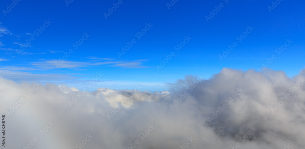 Abstract photograph above the clouds, sea of clouds effect, flying through the sky, aerial view, white puffy clouds and blue sky. Low pressure front atmospheric effect, cloudscape, clear weather.