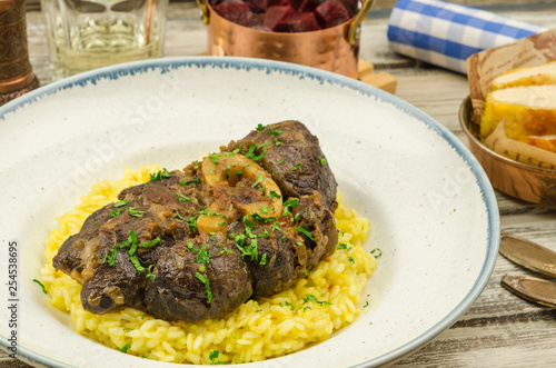 Beef osso bucco with risotto on rustic background.  photo