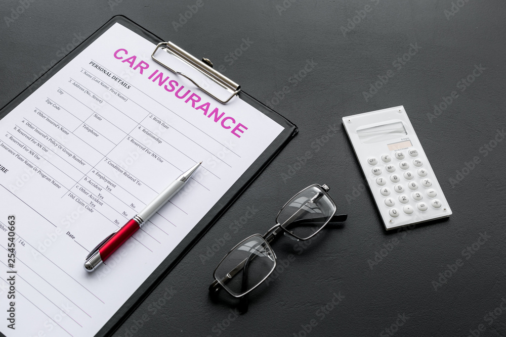 Car insurance form near glasses, calculator, pen on black background Car insurance form near glasses, calculator, pen on black background