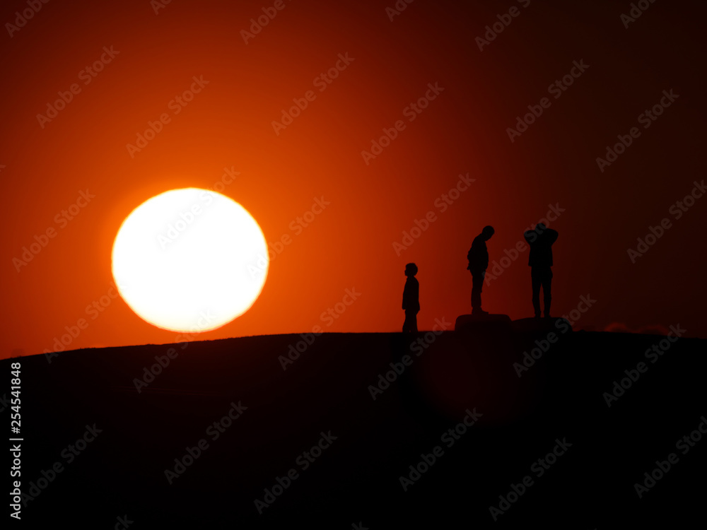 Tokyo,Japan-March 11, 2019: A silhouette of three persons on a hill at sunset