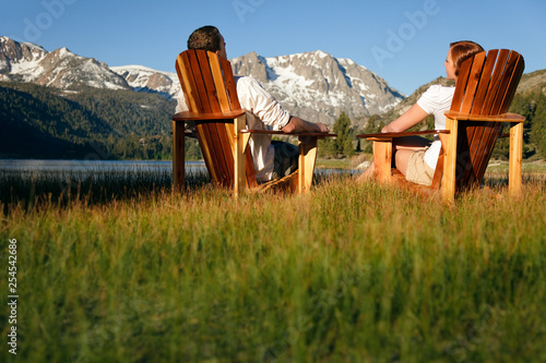 Couple in Adirondack chairs by June Lake with Sierra Nevada Mountains in distance