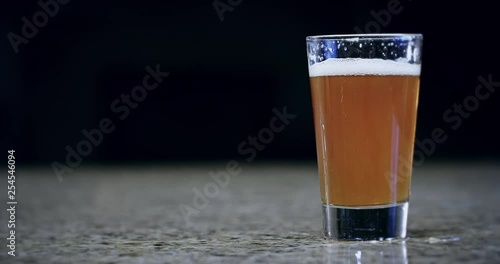 Close up of a pint of beer sliding on a bar in slow motion