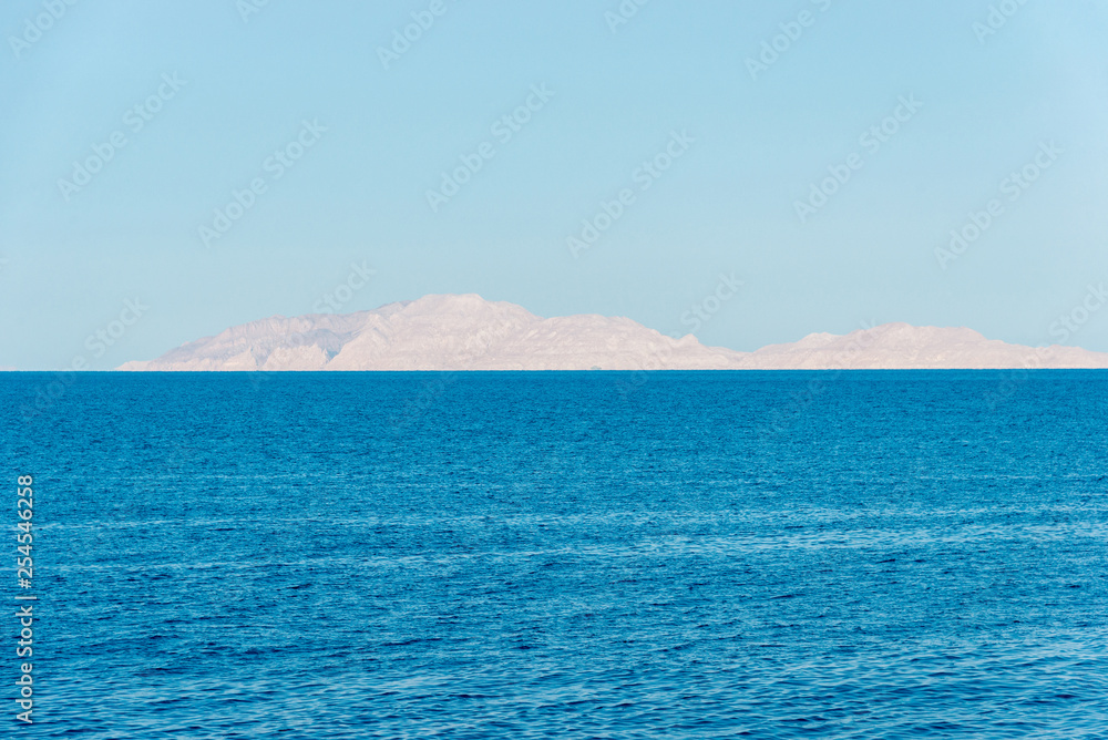 Rocky island in the distance over the beautiful blue sea