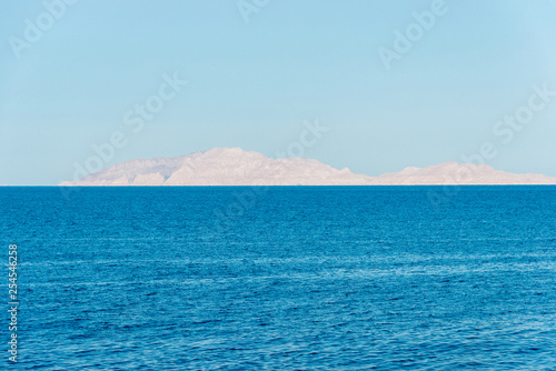 Rocky island in the distance over the beautiful blue sea