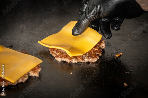 chef with black glove putting cheese on burguer 