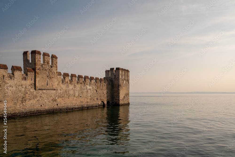 Scenic view of the boundaries of the dockyard of Scaligero Castle, one of the better preserved castles of Italy, over that rare example of lake fortification, Sirmione, Lake Garda, Lombardy, Italy