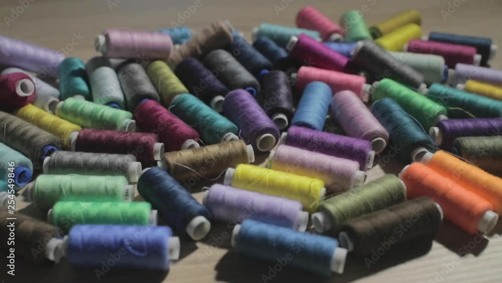 Slow motion video of rolls of strings of different color lie on a table, someone throws a roll of threads on a table Slow motion video of rolls of strings of different color lie on a table, someone throws a roll of threads on a table