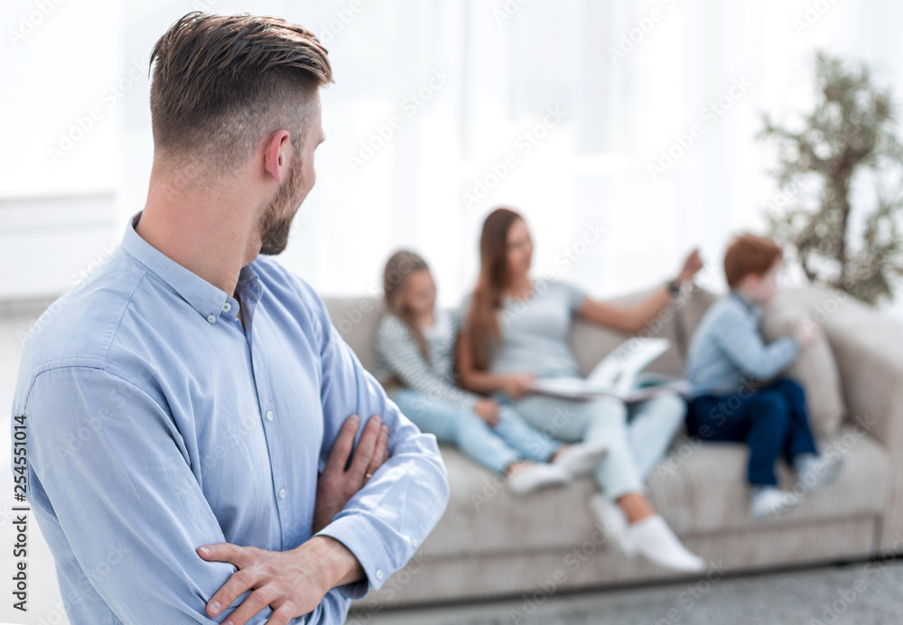 man standing in his living room and looking at his family man standing in his living room and looking at his family