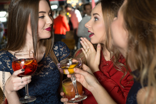 Hypnotic beauty. Three gorgeous young females having drinks at the bar.