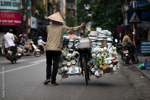 A vietnamese seller with a bike full of porcelain goods for sale in a street of Hanoi, Vietnam. Street Vendor on bicycle.