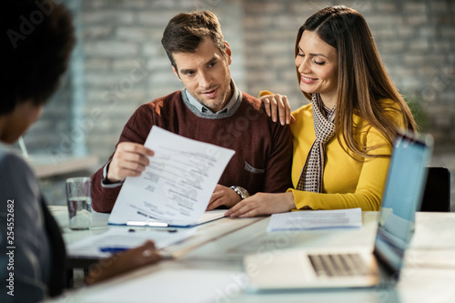 Happy couple going through paperwork on a meeting with insurance agent.