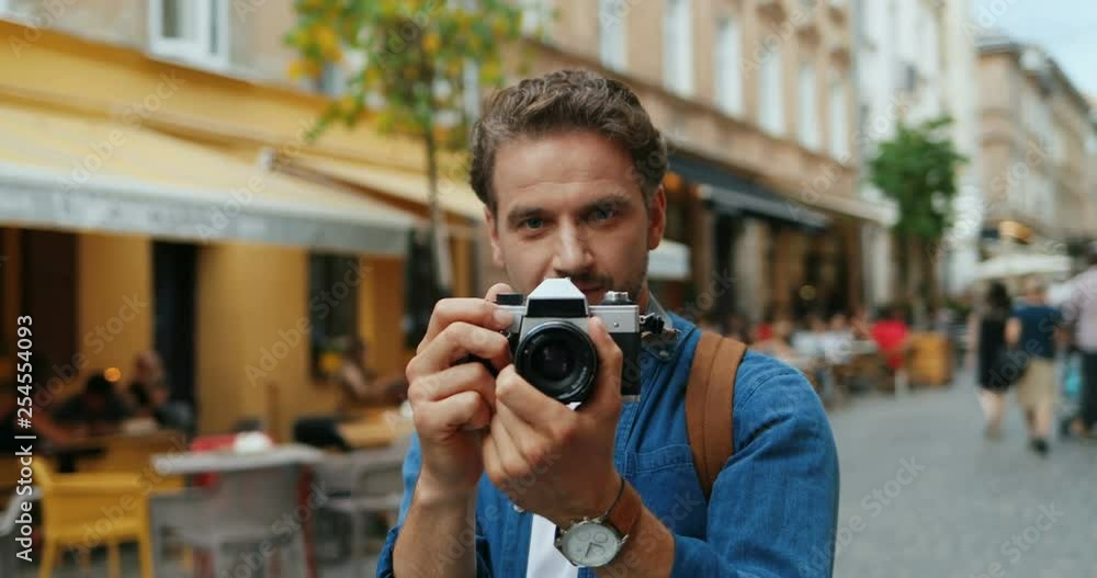 Close up of the young Caucasian man taking photos with a camera on the street. Portrait shot. Close up of the young Caucasian man taking photos with a camera on the street. Portrait shot.