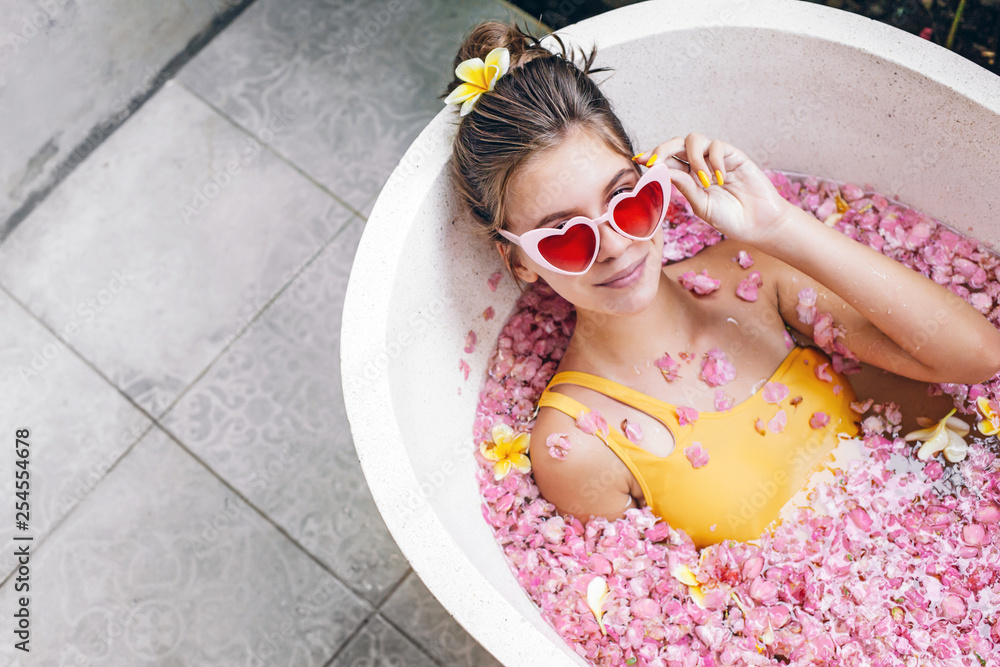 Girl relaxing in spa bath with flowers - obrazy, fototapety, plakaty 