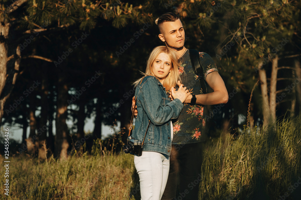 Young amazing couple hugging while traveling outside in their vacation time, where girl is leaning her head on her boyfriend chest while looking away while he is looking in another one. Young amazing couple hugging while traveling outside in their vacation time, where girl is leaning her head on her boyfriend chest while looking away while he is looking in another one.