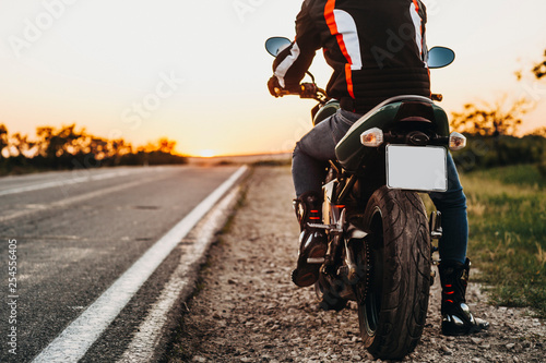 Back view of the motorcycle on the side of the road while bike is on the way for traveling by bike against sunrise.