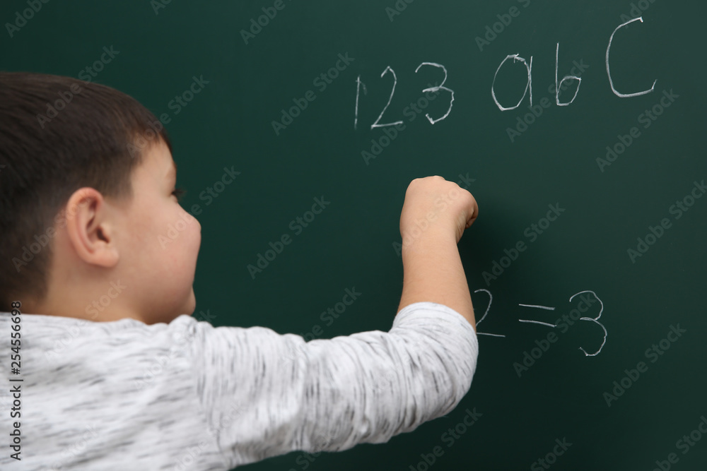 Little child writing math sum on chalkboard Little child writing math sum on chalkboard