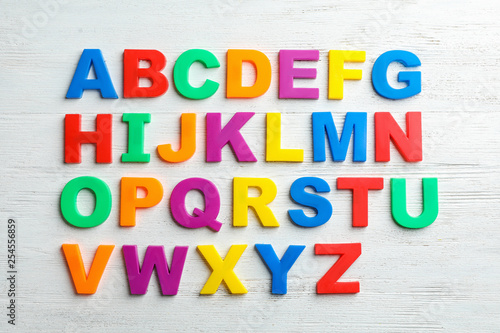 Plastic magnetic letters on wooden background, top view. Alphabetical order