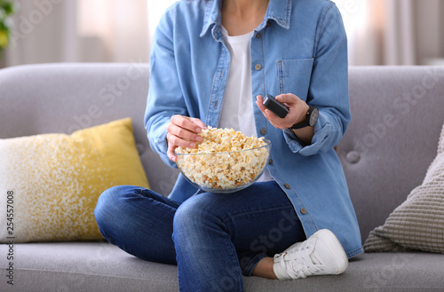 Young woman watching movie with popcorn in living room  closeup