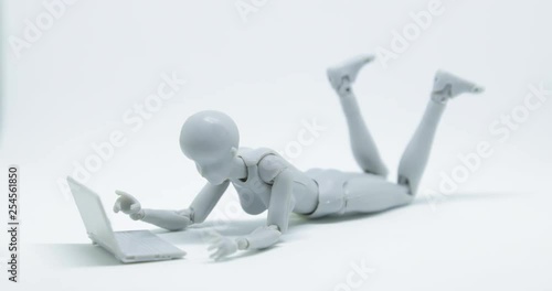 Stop motion footage robot woman is lying down and playing laptop on the floor with with white background.