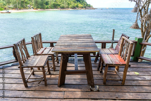 Wooden table and chairs in empty beach cafe next to sea water. Island Koh Phangan, Thailand © OlegD