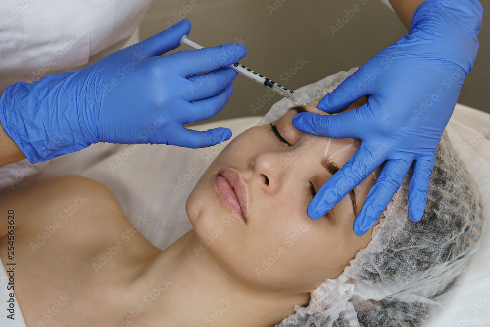 Aesthetic cosmetology. Facelift in spa salon. Beautician makes injections girl in eyebrows. Smoothing of mimic wrinkles. Aesthetic cosmetology. Facelift in spa salon. Beautician makes injections girl in eyebrows. Smoothing of mimic wrinkles.