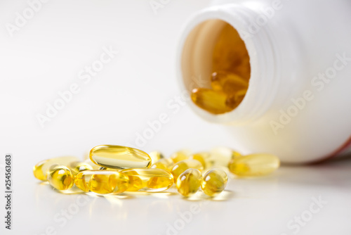Fotografija Fish oil omega 3 gel capsules spilling out of a bottle isolated on white backgro