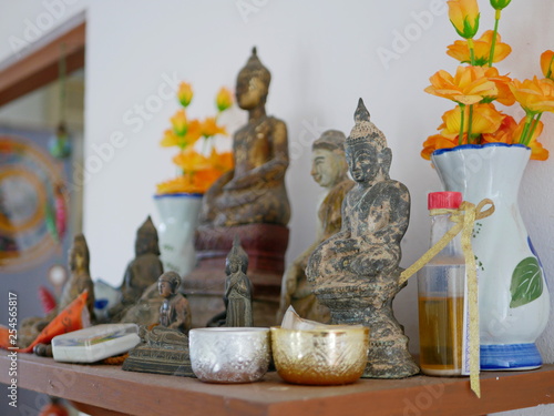 Selective focus of different sizes of Buddha images on a Buddha shelf ( Hing Phra ) at home in Thailand