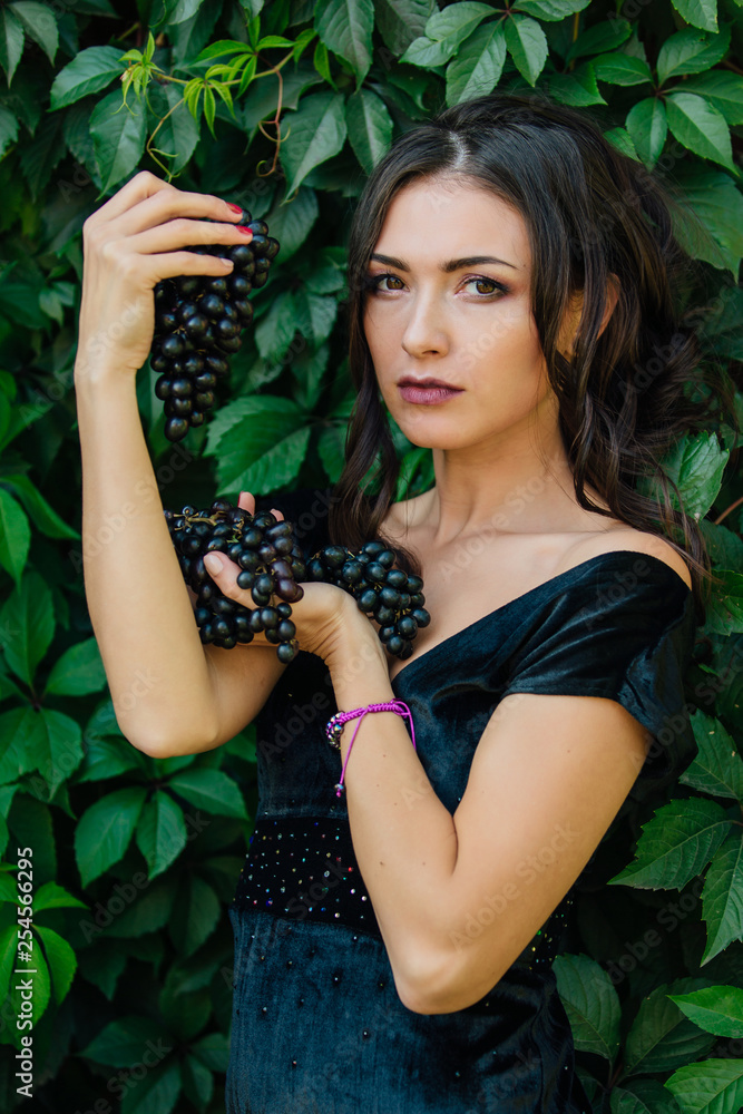 Portrait of young sexy brunette biting black grapes. Portrait of young sexy brunette biting black grapes.
