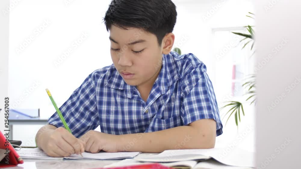 Asian cute boy doing your homework with smile face at home ,4K Dolly shot. Asian cute boy doing your homework with smile face at home ,4K Dolly shot.