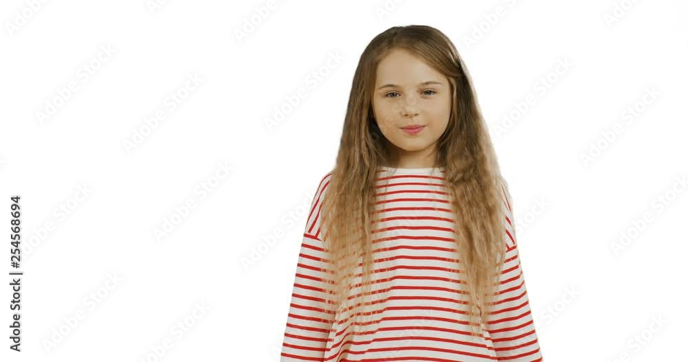 Funny small schoolgirl with long hair standing on the chroma key background, showing her tangue to the camera and crossing her hands. White wall on the back. Funny small schoolgirl with long hair standing on the chroma key background, showing her tangue to the camera and crossing her hands. White wall on the back.